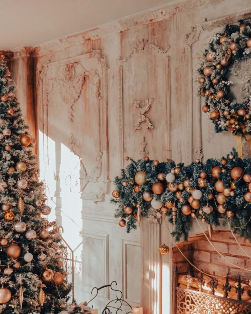 Living room decorated for Christmas with a lit tree beside the fireplace and a garland along the mantel