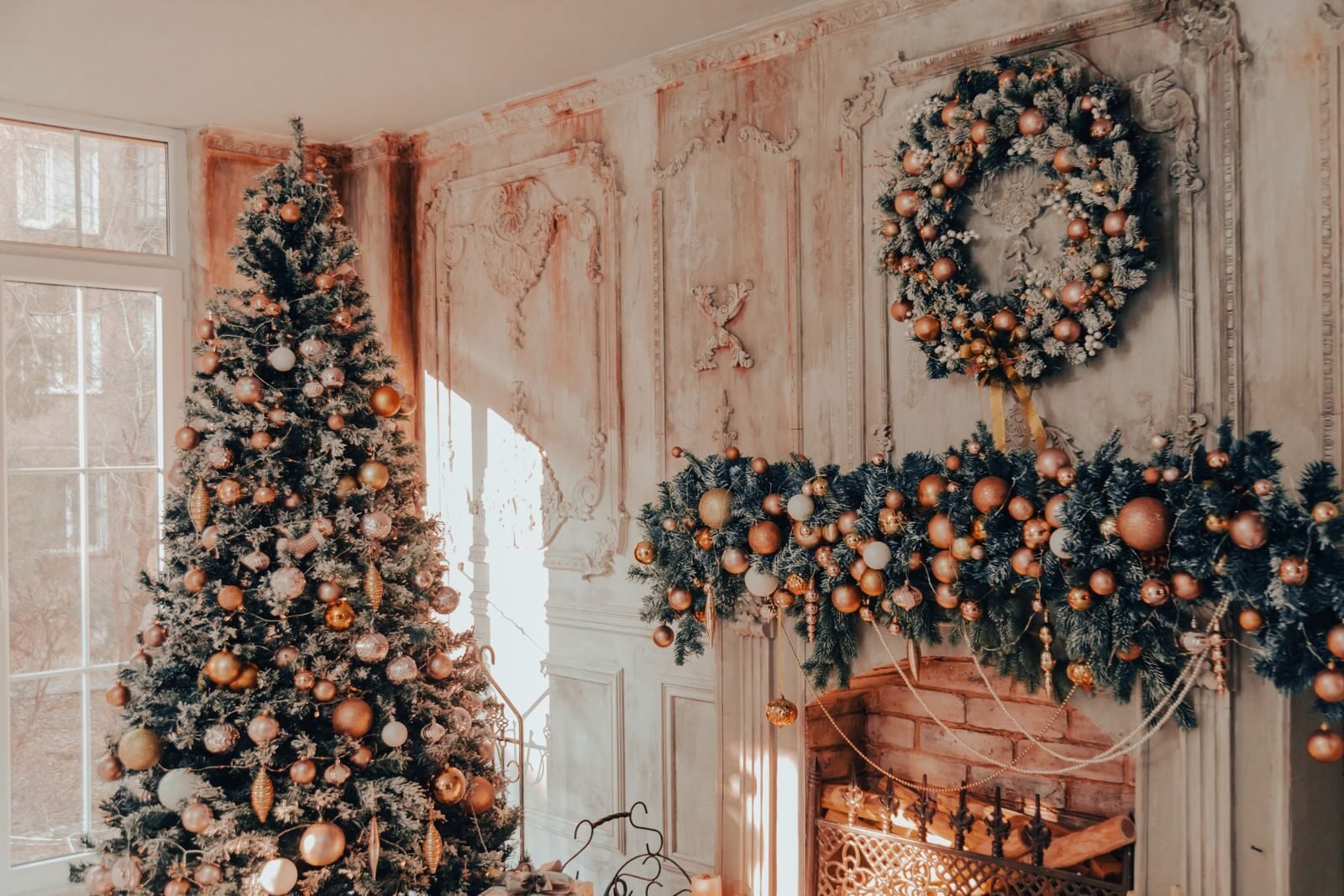 Living room decorated for Christmas with a lit tree beside the fireplace and a garland along the mantel