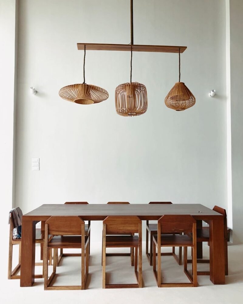 Dining room with a solid wood table and matching chairs beneath a pair of rustic pendant lamps hung low over the table