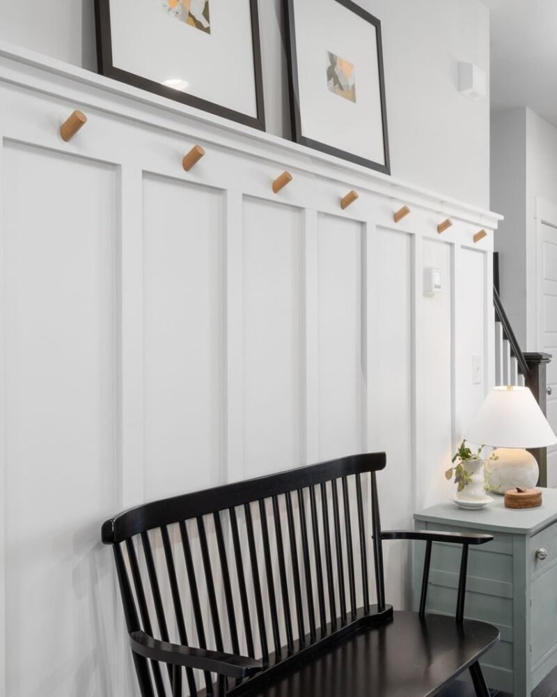 Entryway with a painted green door, a black bench for putting shoes on and baskets stored underneath it