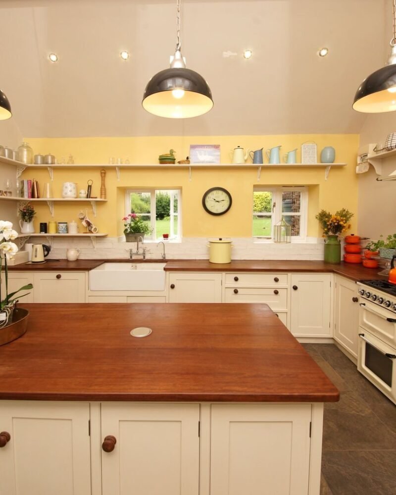 Farmhouse kitchen with open timber shelving holding stacked ceramic bowls above a solid wood countertop