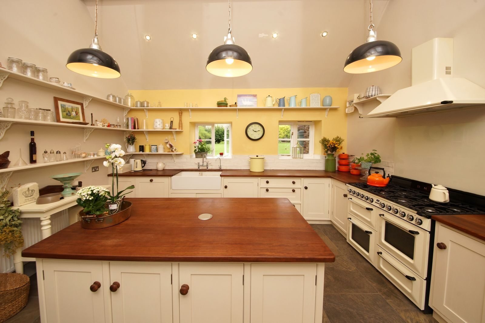 Farmhouse kitchen with open timber shelving holding stacked ceramic bowls above a solid wood countertop