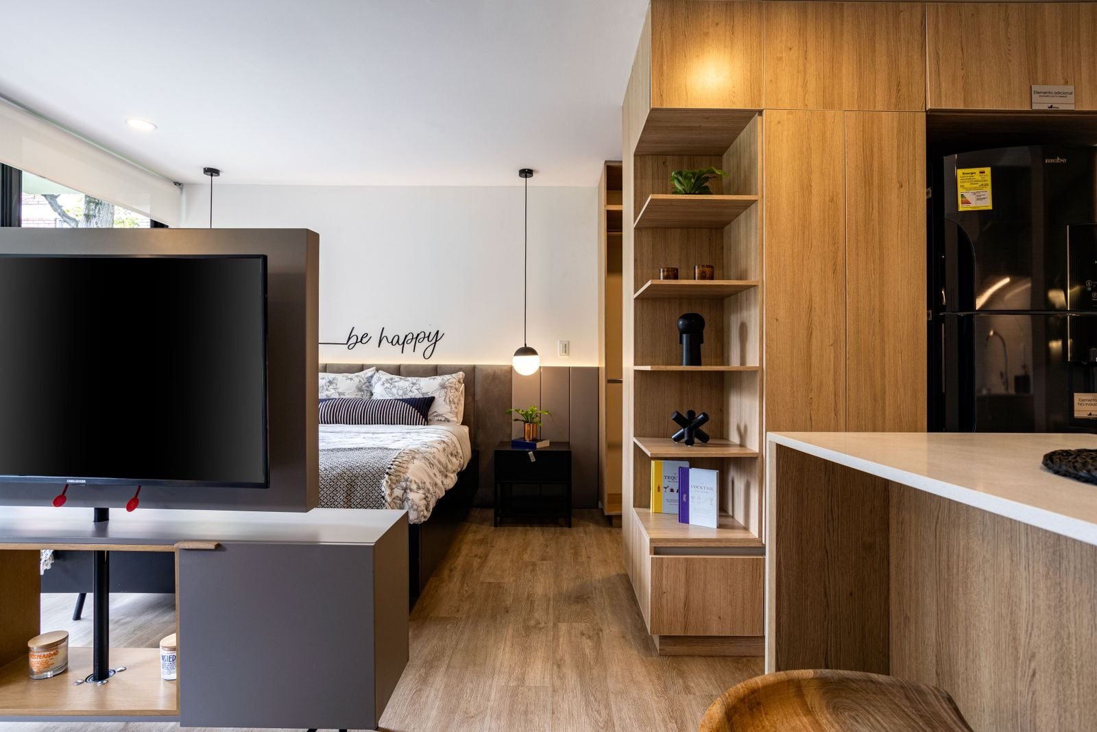 Small studio apartment zoned into sleeping and sitting areas using wooden furniture rather than partitions