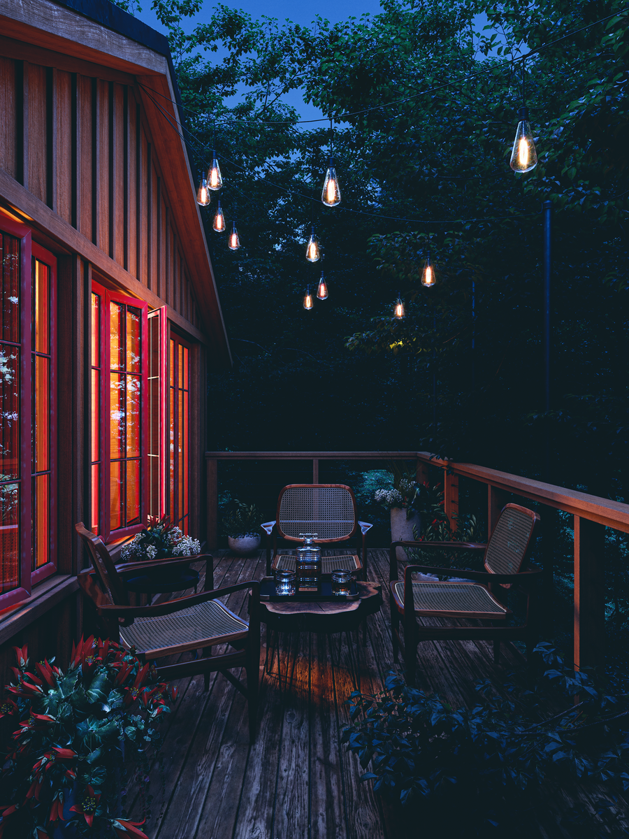 Outdoor seating area on a wooden deck lit by string lights strung overhead at twilight